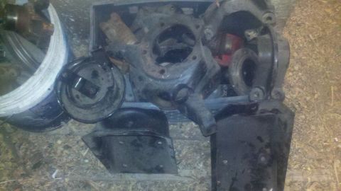 1988 Ford Bronco - Assorted vehicle axle parts are piled together on the ground.