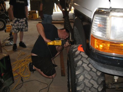 1994 Ford Bronco - A man uses a reciprocating saw to modify the fender flare of a 1994 Ford Bronco to accommodate oversized tires.