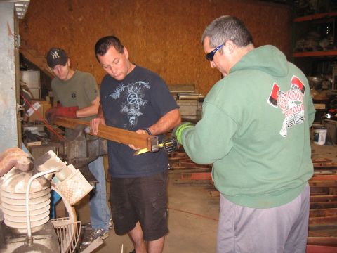 1994 Ford Bronco - Men work on a wooden beam in a workshop, with one man using a saw.