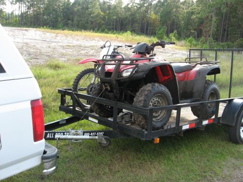 1994 Ford Bronco - A red ATV and a dirt bike are loaded onto a trailer towed by a white truck.
