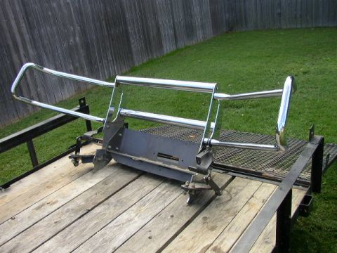 1995 Ford Bronco - Chrome winch bumper with brush guard mounted on a trailer, ready for installation.