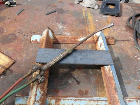 1976 Chevrolet Corvette - A close-up view of a welding torch and hoses rests on a weathered, rusty metal surface with scattered metal scraps.
