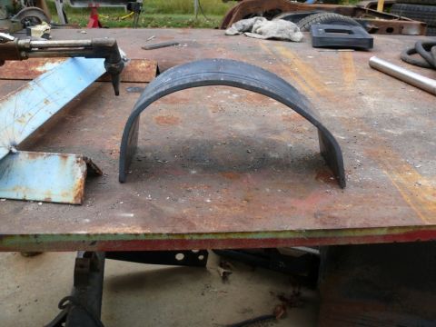 1976 Chevrolet Corvette - A curved metal fender flare sits on a weathered workbench, with a cutting torch nearby.