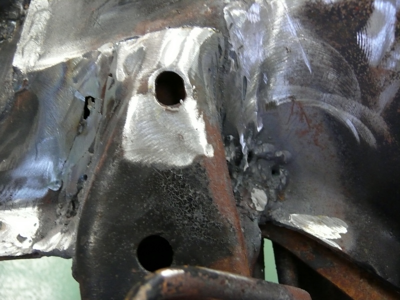 Close-up of welded metal frame with holes, showing signs of repair