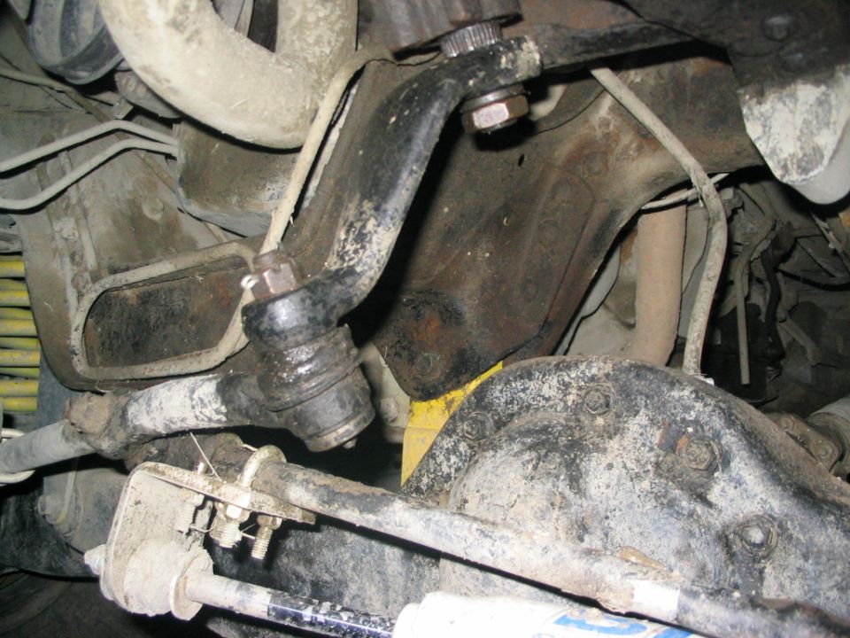 Close-up of vehicle steering linkage and suspension parts, including a ball joint and shock absorber