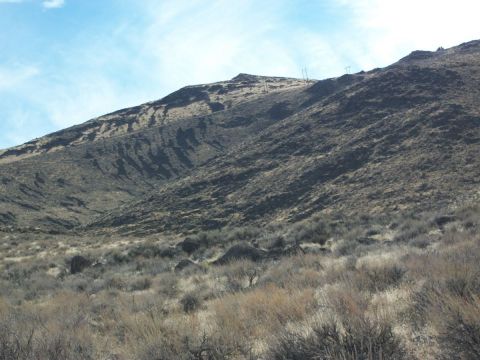 1996 Ford Bronco - A wide view of a dry, arid mountain landscape with sparse vegetation and power lines on the summit.
