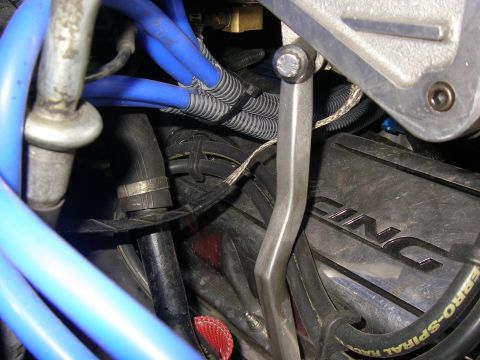 1990 Ford Bronco - Close-up view of an engine bay, showing blue spark plug wires and a black valve cover with partial "ACING" lettering.