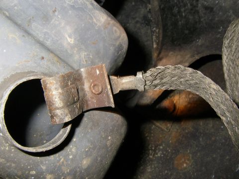1990 Ford Bronco - A close-up view of a vehicle's exhaust system components, including a clamp and braided hose.