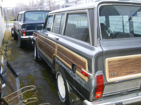 2000 Ford E350 - Two classic Jeep Grand Wagoneers are parked next to each other on a paved surface.