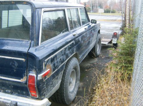 2000 Ford E350 - This dark blue station wagon shows significant wear and rust on its exterior panels. The vehicle is parked outdoors next to a chain-link fe…