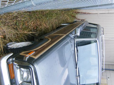 2000 Ford E350 - Front corner of a gray Ford Econoline van, showing woodgrain trim and a spare tire mounted on the fender.