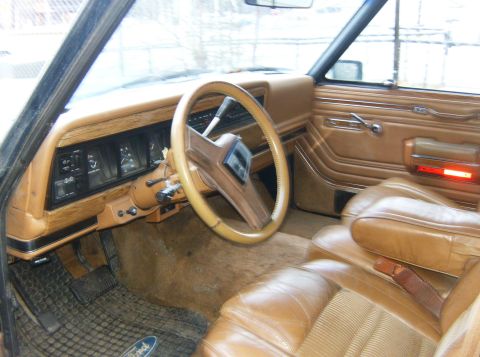 2000 Ford E350 - Interior of a vintage SUV with tan upholstery and wood-grain trim, a Ford floor mat.