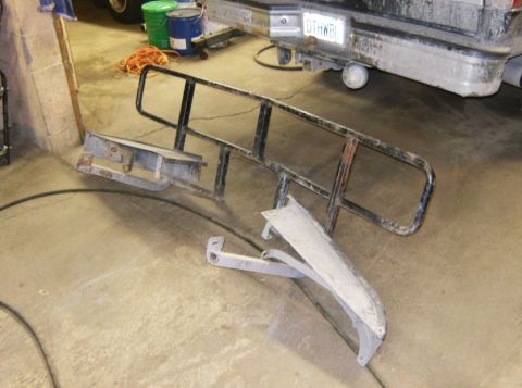 2000 Ford E350 - Disassembled truck bumper and grille guard components lie on a concrete floor, with a vehicle's rear visible in the background.