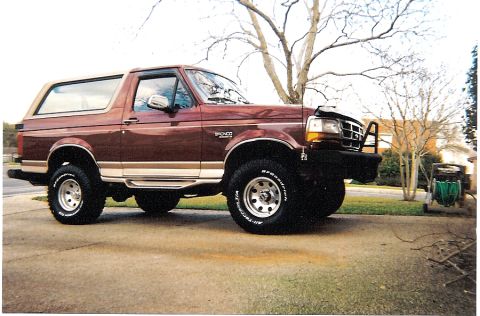 1988 Ford Bronco - Maroon 1988 Ford Bronco with tan top and aftermarket bumper parked on a driveway.