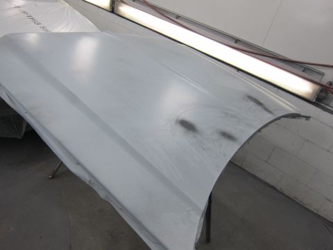 1987 Dodge 1500 - A car hood is prepared for painting in a workshop environment.