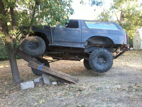 1986 Ford Bronco - Ford Bronco modified for off-road use, positioned on a makeshift ramp.