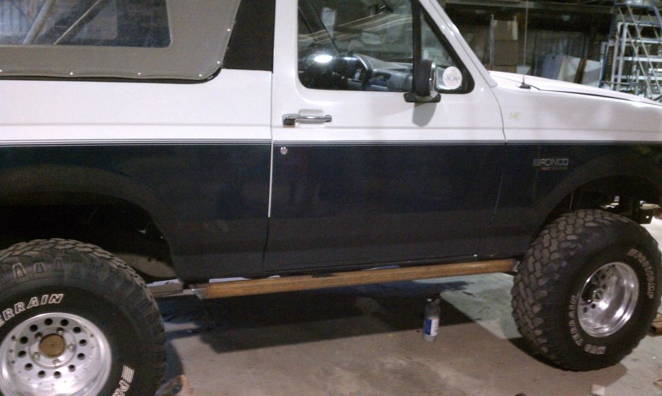 Side view of a white and dark blue Ford Bronco with off-road tires