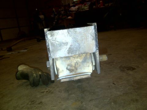 1979 Ford E250 - A close-up view of a metal engine mount with a rubber insulator, resting on a concrete floor next to a work glove.