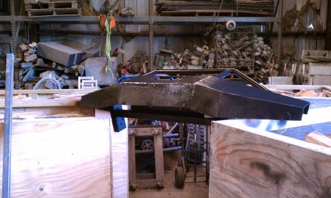 1979 Ford Bronco - This custom car body part is seen in a workshop setting, surrounded by various materials and equipment.