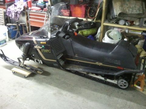 1985 Ford Bronco - A black Yamaha snowmobile with gold trim and GT badging is parked indoors.