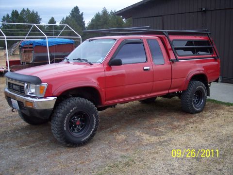 1991 Toyota Pickup/SR5 - This red Toyota pickup truck, likely a 1991 model, is equipped with a camper shell and roof rack.