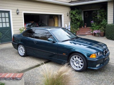 1998 BMW M3 - A dark green 1998 BMW M3 coupe is parked in front of a garage and house.