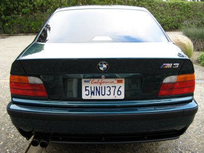 1998 BMW M3 - Rear view of a dark green 1998 BMW M3 sedan, showing its distinctive taillights and M3 badging.