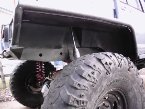 1986 Ford Bronco - The underside of a modified vehicle is shown, focusing on its heavy-duty off-road tire and suspension system.