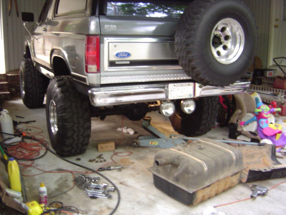 Gray Ford Bronco rear, lifted with large tires, spare tire mounted, gas tank removed