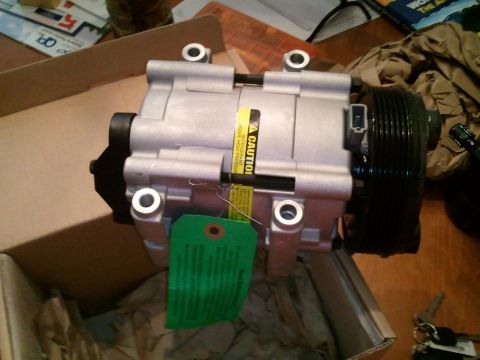1994 Ford Bronco - A new AC compressor is shown, complete with a caution label and a green inspection tag attached.