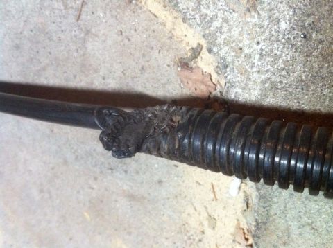 1989 Ford Bronco - Close-up of damaged electrical conduit showing melted plastic and ribbed casing.