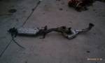 1994 Ford Probe - A detached exhaust system component rests on a rough surface, possibly awaiting installation or disposal.