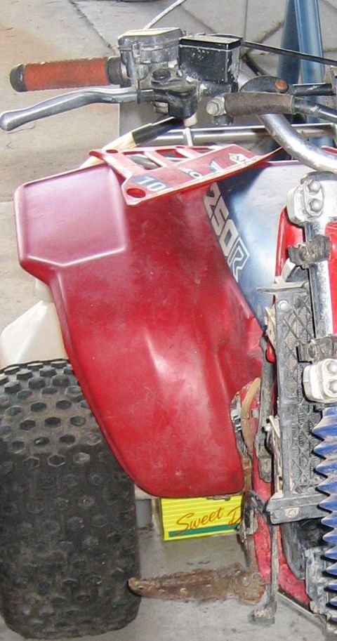 1900 Honda Big Red - Close-up view of the front fender and handlebars of an ATV, with "250R" branding visible on the side panel.