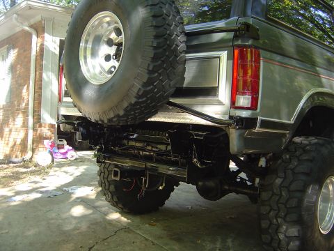 1986 Ford Bronco - Rear view of a lifted Ford Bronco, showing the bumper, spare tire, and suspension.