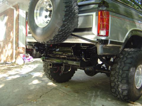 1986 Ford Bronco - The rear of a lifted SUV is shown, a spare tire and custom bumper modifications.