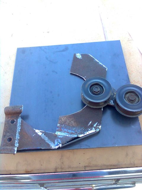 1984 Ford Bronco - Custom metal bracket with two pulleys, welded construction, resting on a blue metal plate.