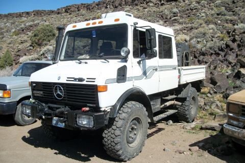 1996 Ford Bronco - A white Mercedes-Benz Unimog 1300L is parked outdoors with a rocky hillside in the background.