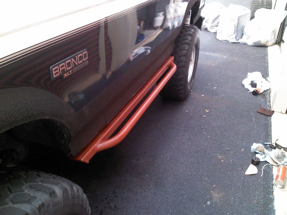Dark blue Ford Bronco XLT with orange side steps and large tires