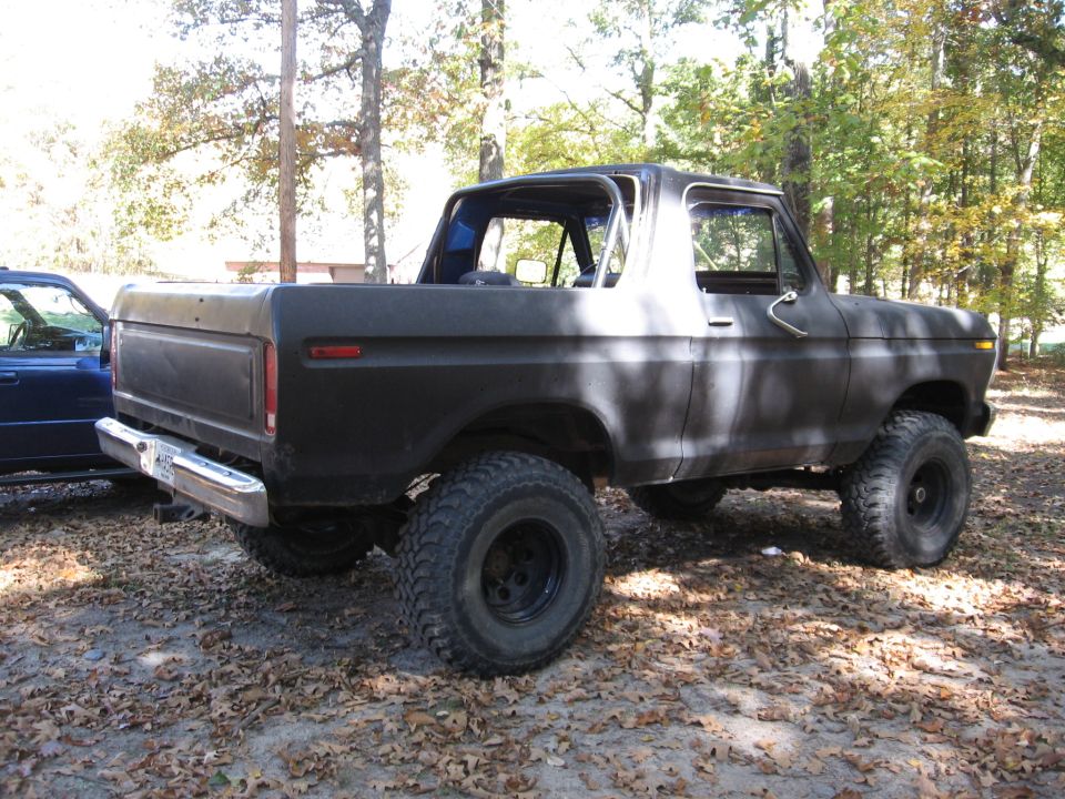 Black 1978 Ford Bronco with lifted suspension and large tires, viewed from the rear three-quarter angle