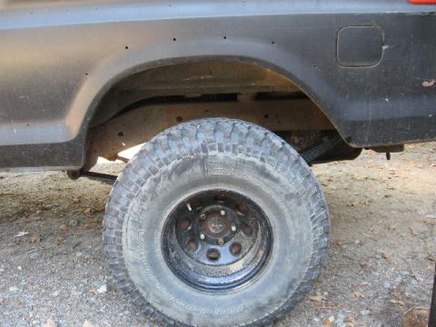 1978 Ford Bronco - The rear wheel well and tire of a black 1978 Ford Bronco are visible, showing BFGoodrich All-Terrain T/A tires.