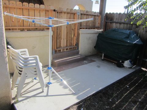 1968 Ford Mustang - A backyard patio area is shown with a clothesline, chairs, and a grill covered with a green tarp.