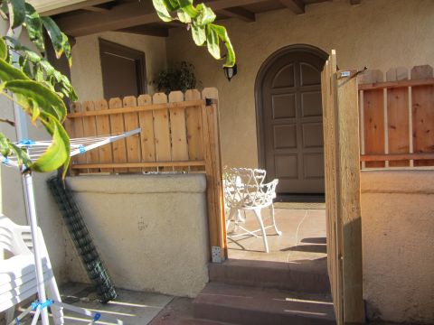 1968 Ford Mustang - A sunny front porch scene with a white chair and a wooden fence leading to an arched doorway.