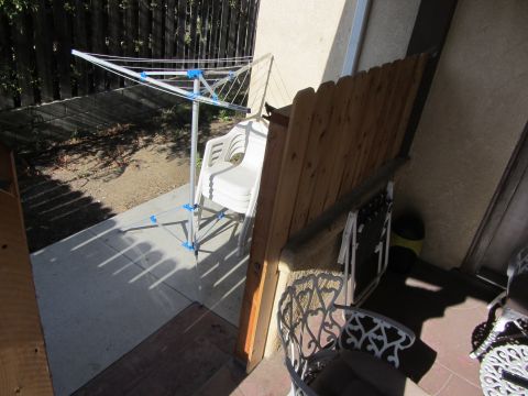 1968 Ford Mustang - An outdoor patio area is depicted with a clothesline and stacked chairs, adjacent to a wooden fence and building wall.
