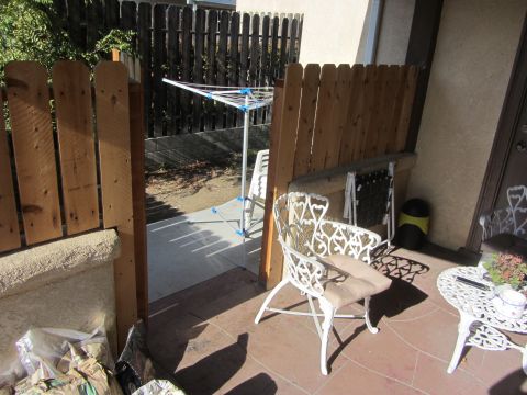 1968 Ford Mustang - A sunny patio scene features white ornate chairs, a clothesline, and a wooden fence, with bags of soil near the entrance.