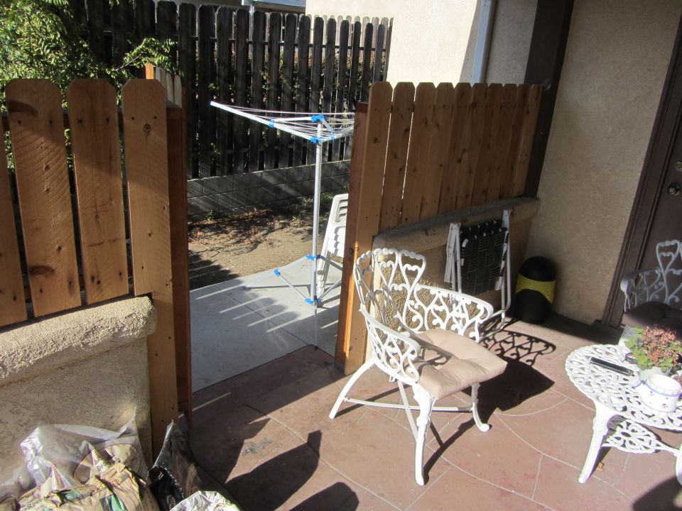 Patio scene with white ornate chairs, clothesline, and wooden fence