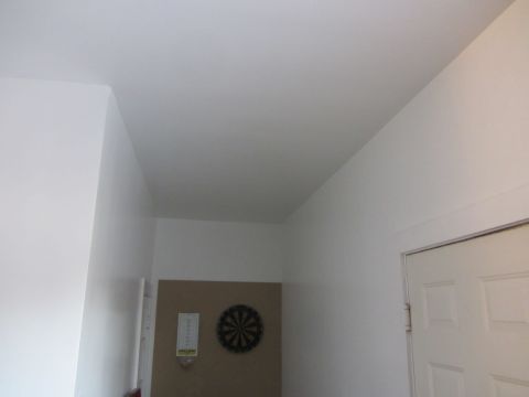 1968 Ford Mustang - A dartboard hangs on the wall next to a door in a room with white walls.