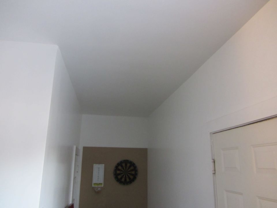 Interior room with white walls, a dartboard on a tan wall, and a white door