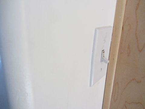 1968 Ford Mustang - A simple light switch is visible on a wall, adjacent to a wooden door frame.