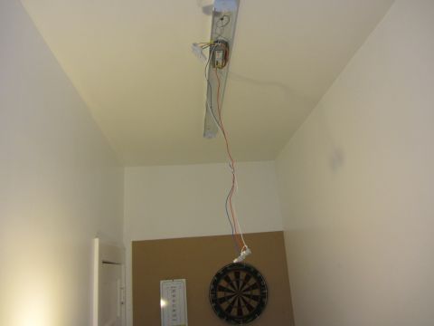 1968 Ford Mustang - The wiring for a fluorescent light fixture is exposed, with a dartboard visible on the wall below.