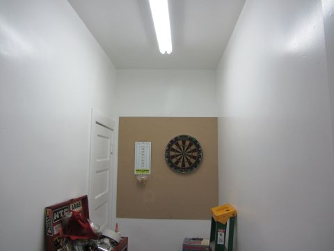 1968 Ford Mustang - A dartboard and a thermometer hang on a corkboard in a room with white walls and a fluorescent light fixture.